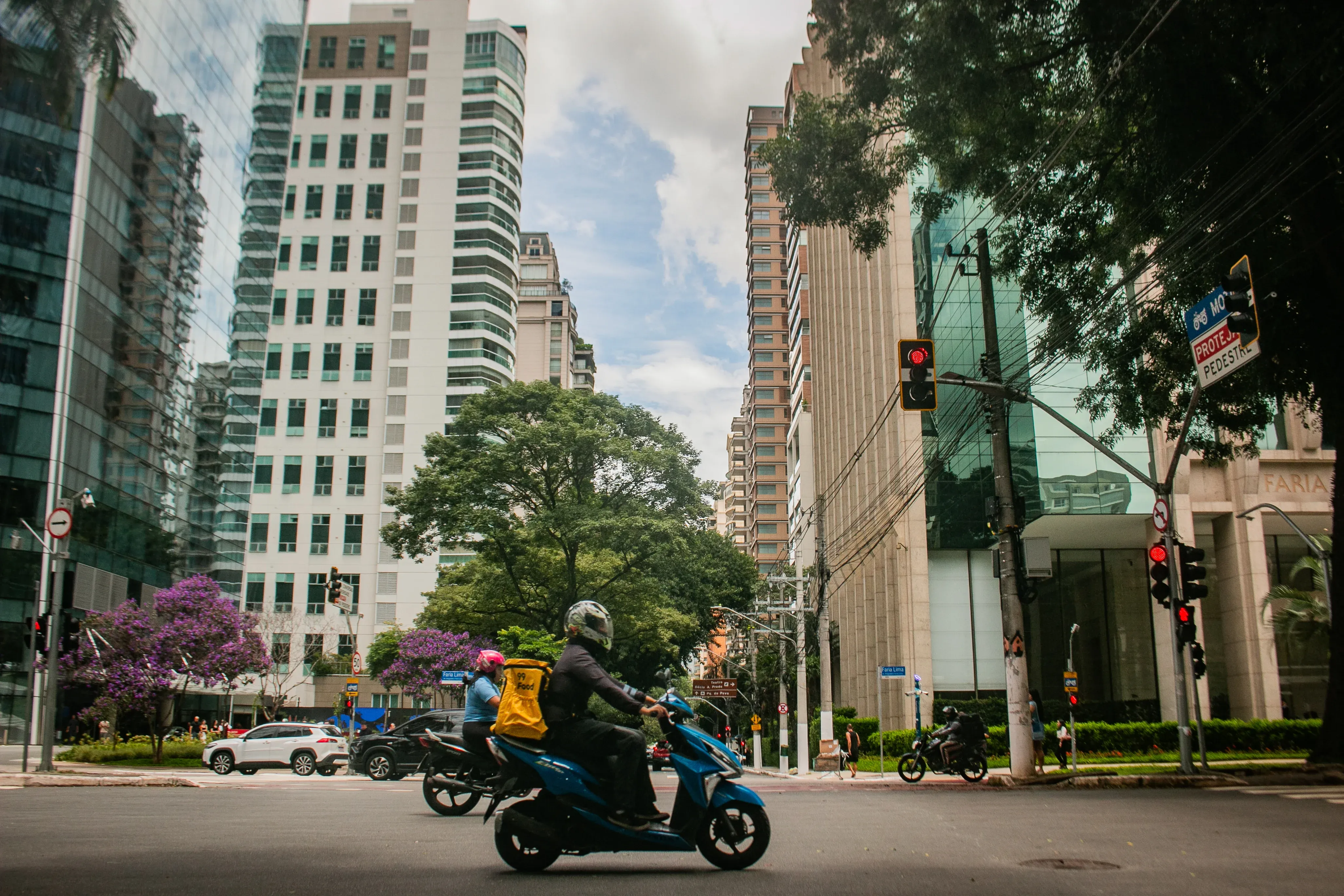 Urban intersection with motorcyclists and delivery rider among high-rise buildings