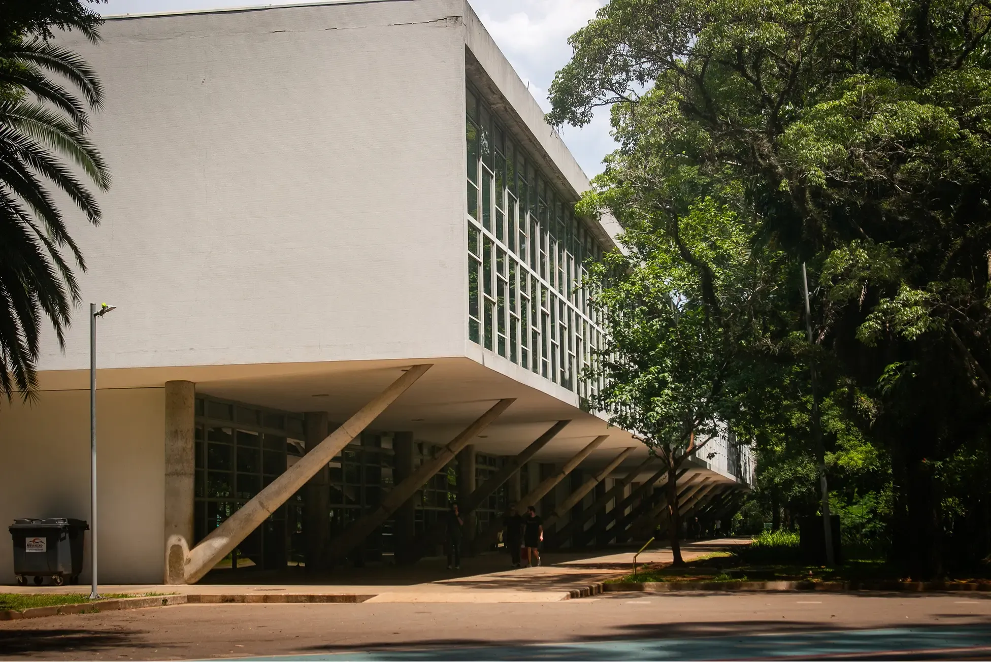 Modernist white building with slanted columns and trees