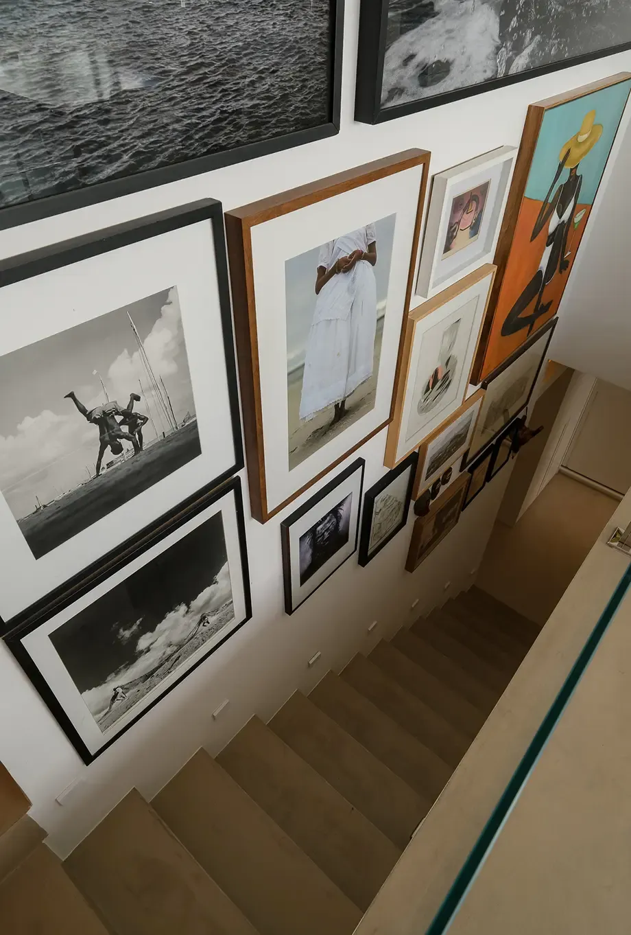 Stairwell with a gallery wall of framed photos and art above wooden steps