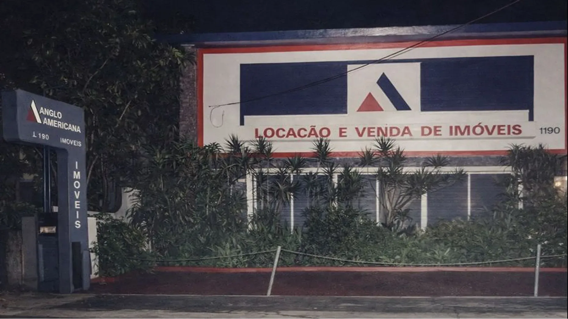Vintage Anglo Americana real estate office at night with a facade sign for property sales and rentals