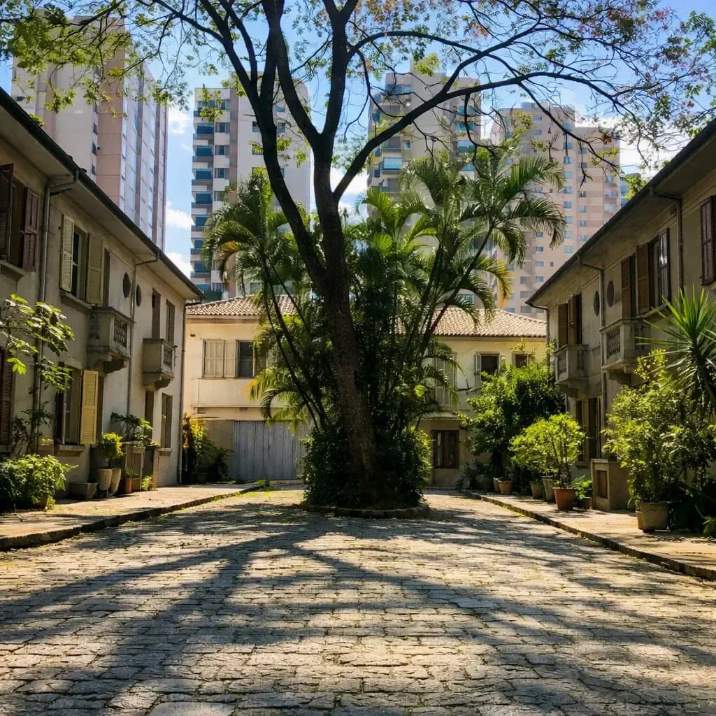 Cobblestone courtyard with a large central tree between historic low-rise houses